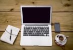 Mesa de trabalho com notebook, café, caderno e celular