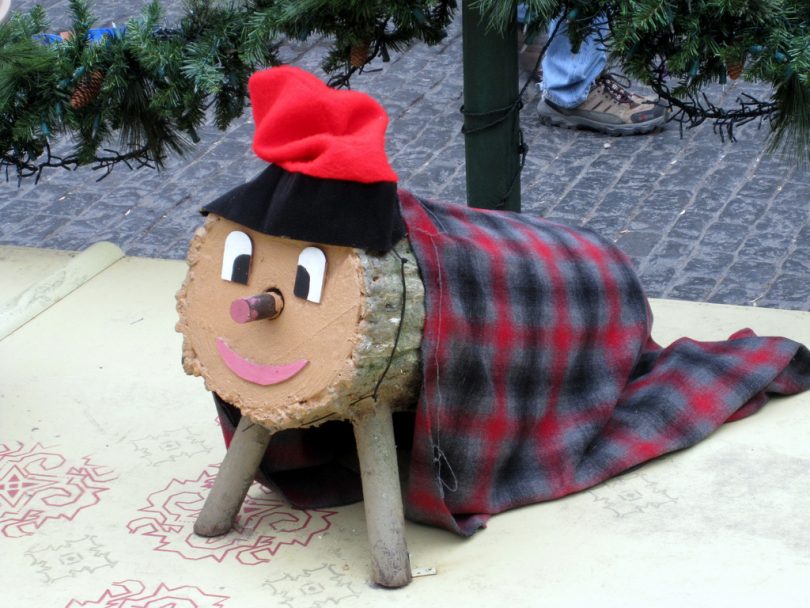 Imagem de tronco de madeira com manta e gorro vermelho