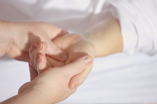 Imagem de uma massagista massageando a mão de um paciente