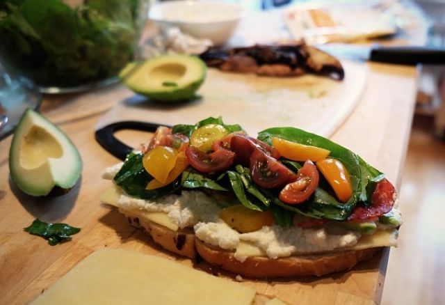 Uma torrada com guacamole, tomate, entre outros ingredientes