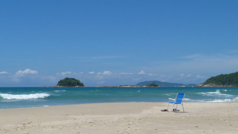 Imagem de praia vazia e céu limpo