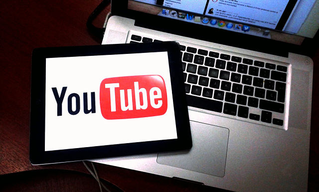 Tablet em cima de um notebook mostrando o logo do YouTube