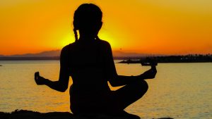 Imagem de mulher meditando na praia