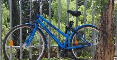 Imagem de uma bicicleta azul encostada em grades