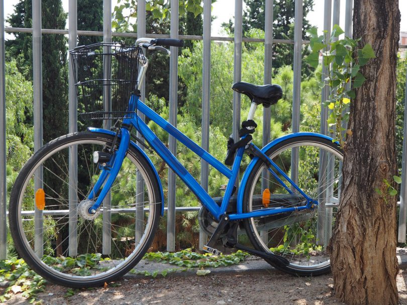 Imagem de uma bicicleta azul encostada em grades