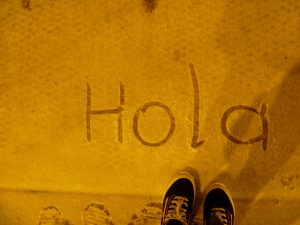 Trabalhar em Barcelona sem falar espanhol é possível, mas aprender o idioma será de grande ajuda para sua adaptação à cidade Imagem da palavra 'Hola' escrita no chão