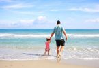 Imagem de pai e filha andando na praia