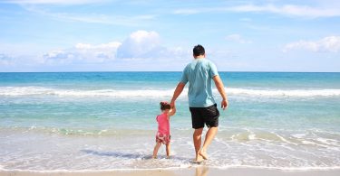 Imagem de pai e filha andando na praia