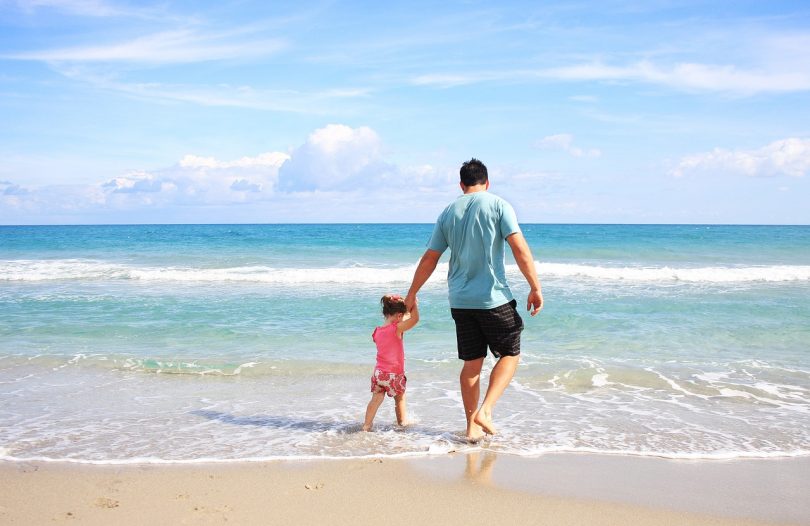 Imagem de pai e filha andando na praia