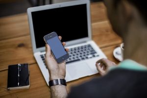 Imagem de homem com celular e laptop