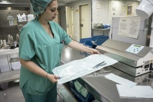 Enfermeira com uniforme verde com utensílios médicos em mãos