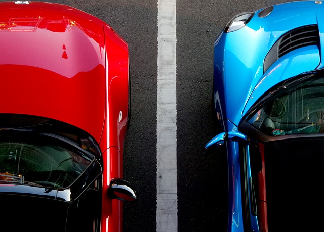 Imagem de carro vermelho e carro azul brilhantes um ao lado do outro em estacionamento