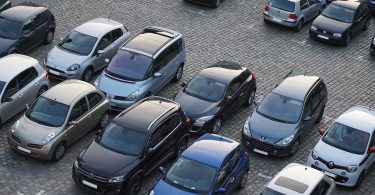 Imagem de carros em fila estacionados em estacionamento a céu aberto