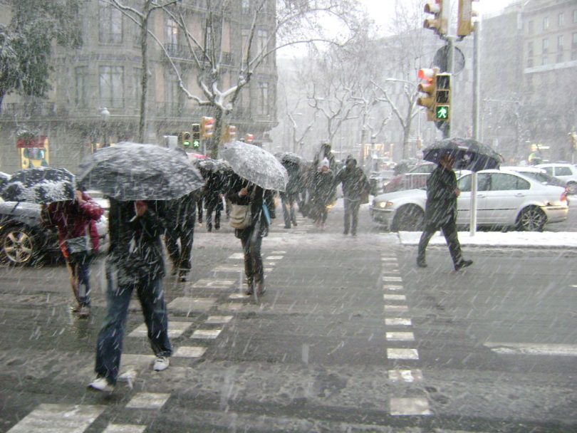 Imagem de pessoas atravessando rua sob neve