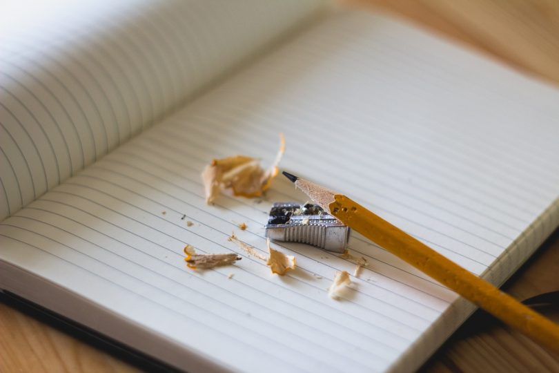 Imagem de um lápis com apontador sobre caderno