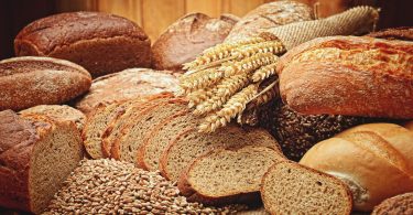 Imagens de vários tipos de pão e trigo sobre mesa de madeira
