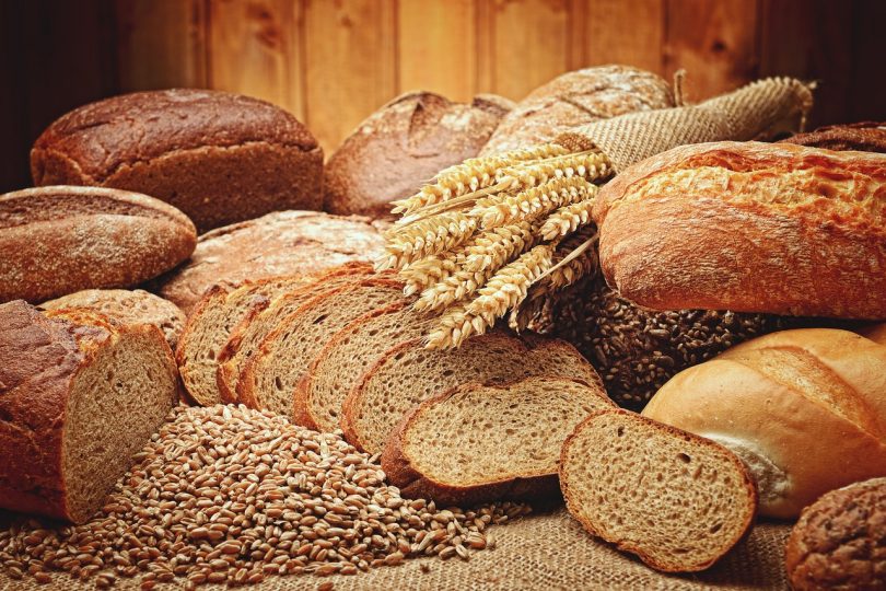 Imagens de vários tipos de pão e trigo sobre mesa de madeira