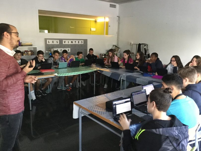 Imagem de alunos com pequenos computadores à frente sobre mesas