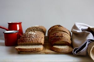Imagem de pão de massa madre sobre mesa com bule de café e toalha