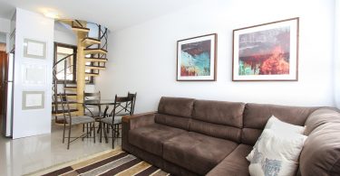 Imagem de sofá em sala com escada ao fundo