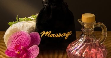 Imagem de óleo, pétalas de rosa e toalha para massagem