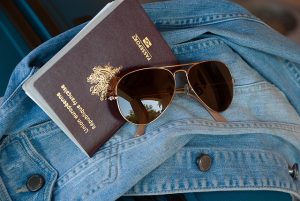 Imagem de óculos de sol, jaqueta e um passaporte