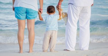 Famíia com jovem filho observando o movimento das ondas do mar