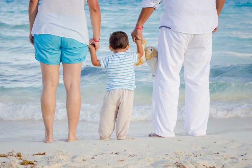 Famíia com jovem filho observando o movimento das ondas do mar