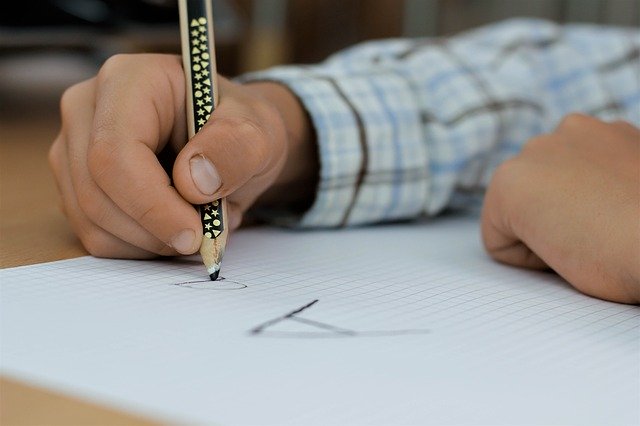 Criança escreve letras em seu caderno