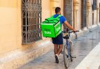 Homem carrega a caixa do Uber Eats enquanto faz entrega