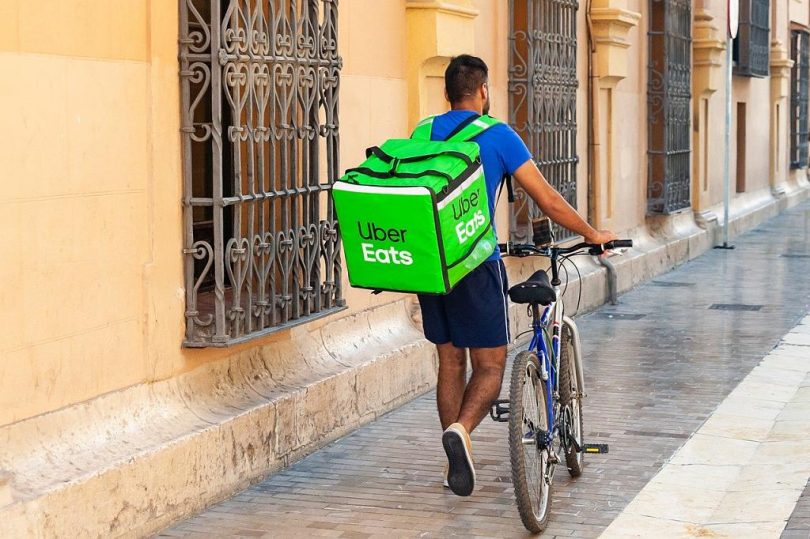 Homem carrega a caixa do Uber Eats enquanto faz entrega