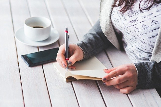 Mulher escrever algumas anotações no seu caderno